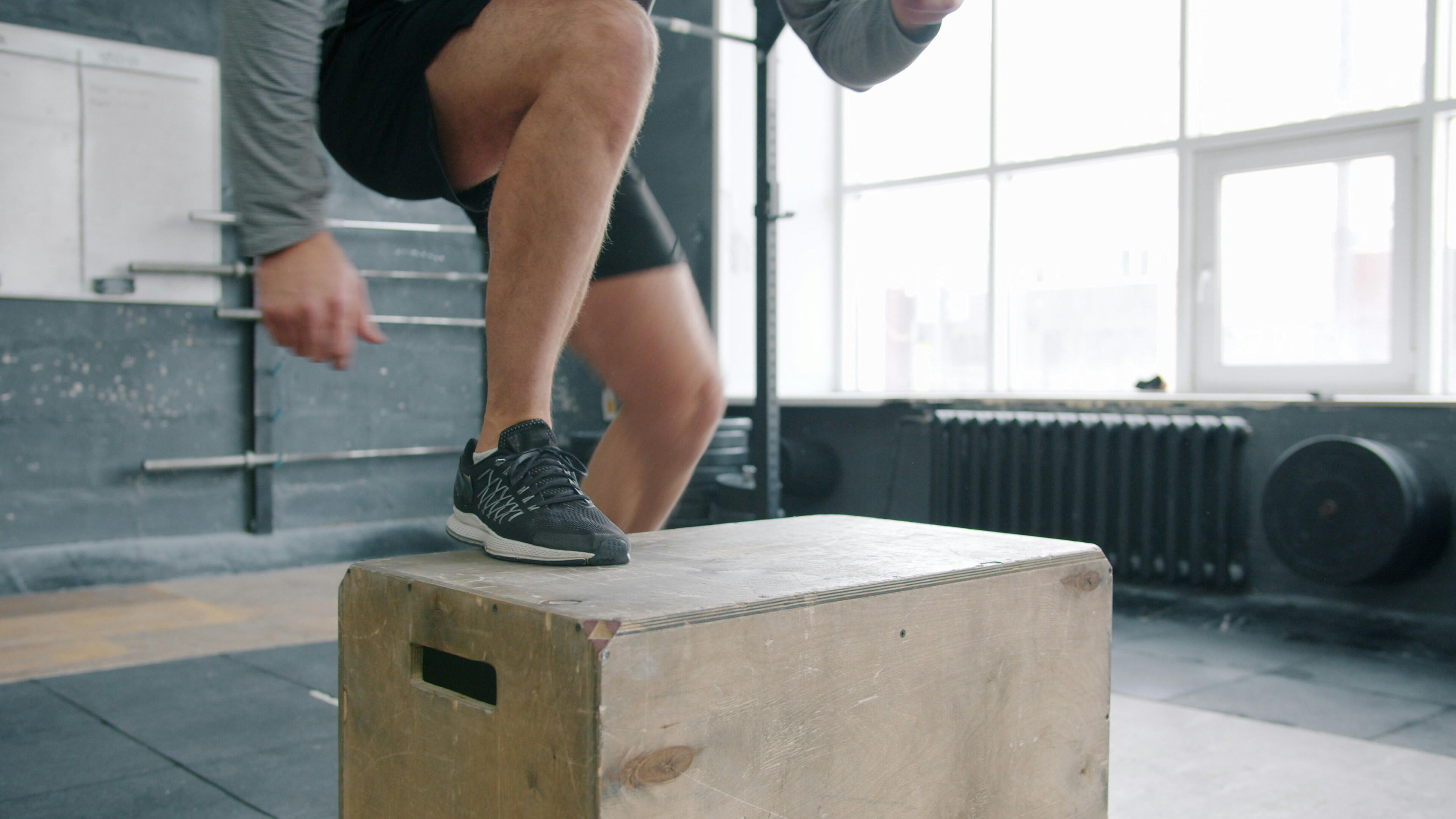 A person stepping onto a plyometric box to mimic a realistic motion of stepping up onto something and pushing yourself up.
